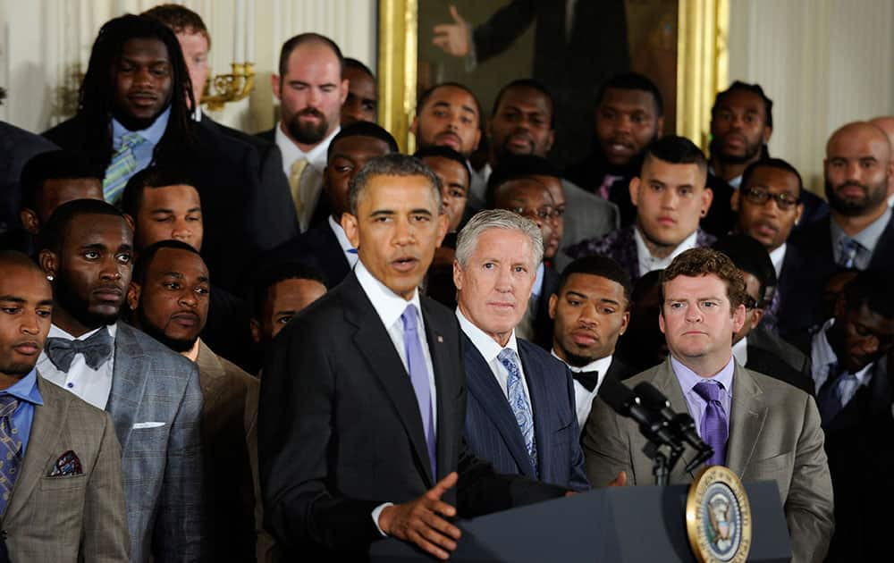 Seattle Seahawks Executive Vice President of Football Operations and Head Coach Pete Carroll, center, and Executive Vice President/General Manager John Schneider, right. and others, listen as President Barack Obama speaks in the East Room of the White House in Washington.