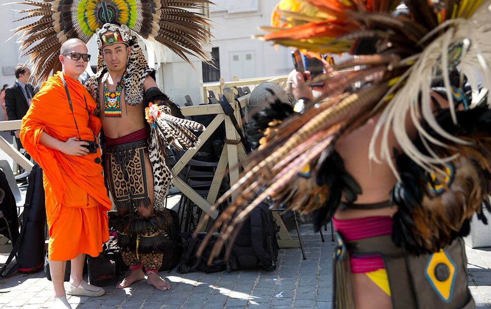 A member of a group of representatives from various indigenous people, right, takes pictures with a mobile phone during Pope Francis weekly general audience in St. Peter`s Square at the Vatican.