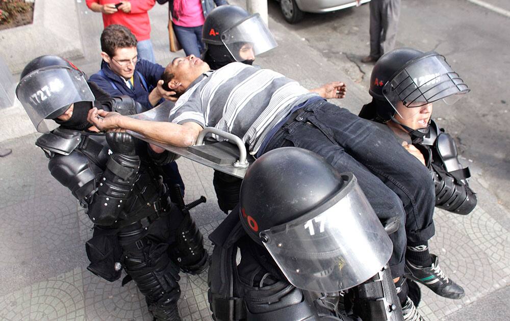 Riot police carry a passerby who fainted due to the tear gas used by the police as they dispersed a group of hooded students who blocked the avenue in front of the National University in Bogota, Colombia.