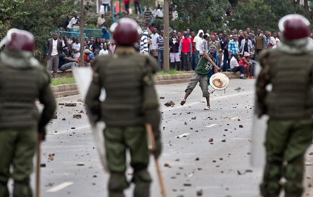 A student carrying a makeshift shield throws rocks at riot police as they engage in running battles on the highway next to Nairobi University`s main campus in downtown Nairobi, Kenya.