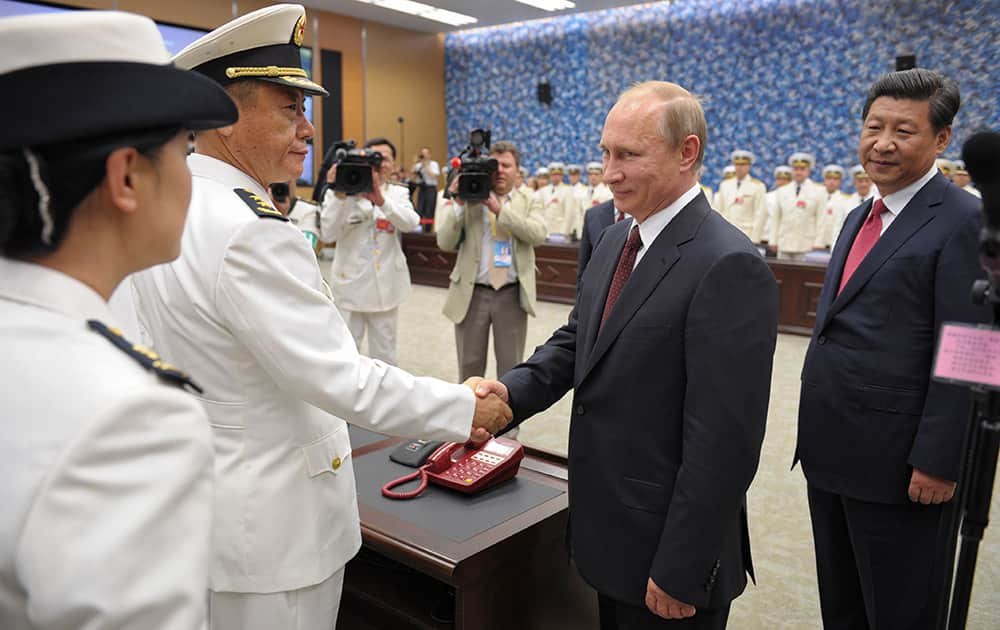 Russia`s President Vladimir Putin shakes hands with a Chinese naval officer, with China`s President Xi Jinping at right, as they open joint naval exercises in Shanghai, China.