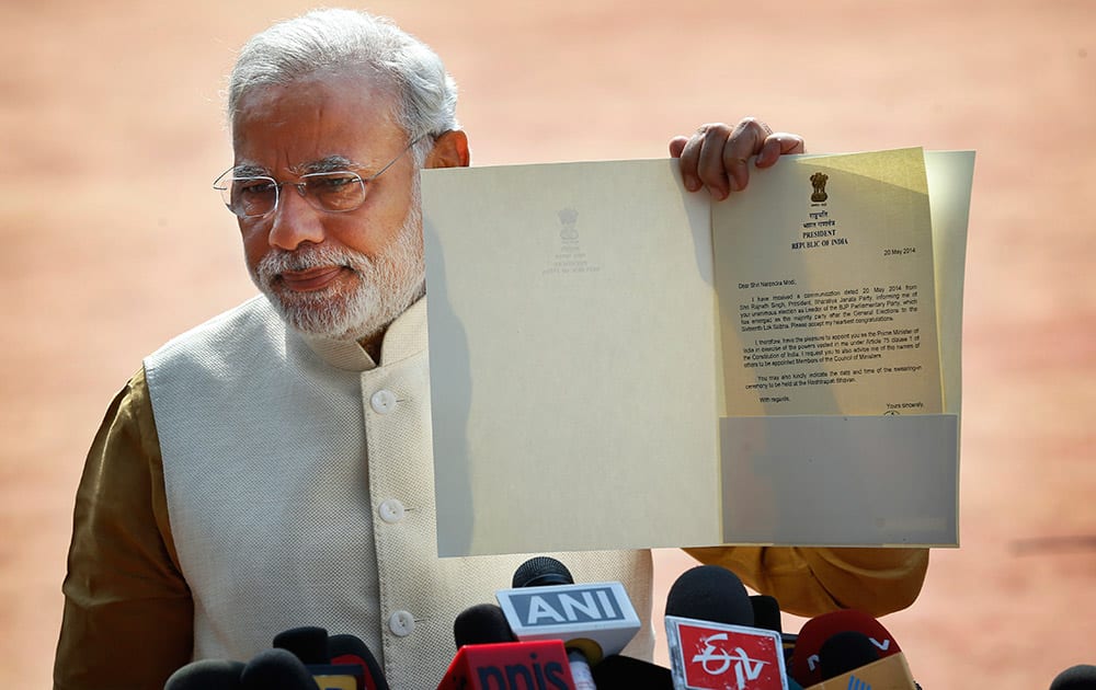 Narendra Modi displays the letter from the Indian President inviting him to form the new government, outside the Presidential Palace in New Delhi.