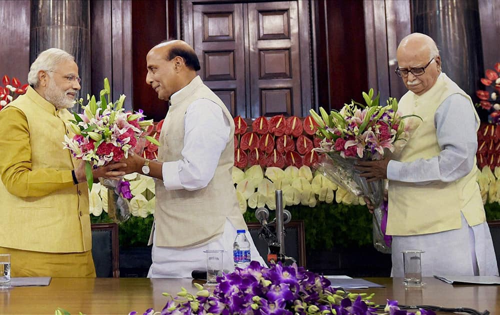 Narendra Modi receives a bouquet of flowers from party President Rajnath Singh, as senior leader Lal Krishna Advani waits to greet Modi during the BJP parliamentary party meeting in New Delhi.