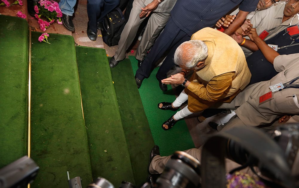 Narendra Modi bends down with folded hands on the steps of the Indian parliament building as a sign of respect as he arrives for the BJP parliamentary party meeting in New Delhi.