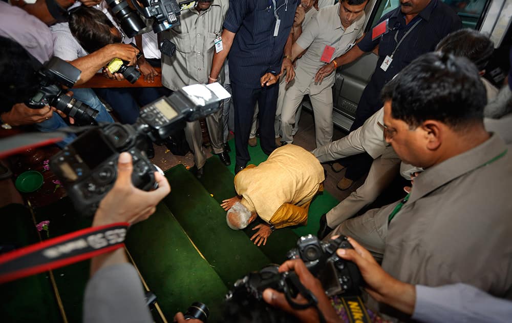 Narendra Modi bends down on his knees on the steps of the Indian parliament building as a sign of respect as he arrives for the BJP parliamentary party meeting in New Delhi.