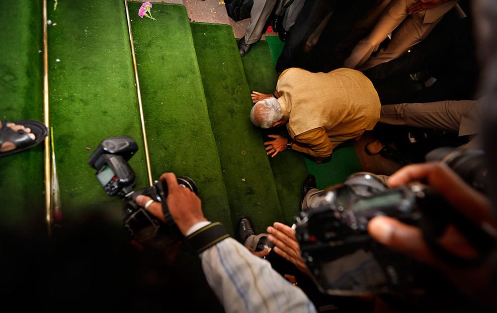 Narendra Modi bends down on his knees on the steps of the Indian parliament building as a sign of respect as he arrives for the BJP parliamentary party meeting in New Delhi.