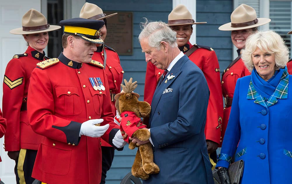 Prince Charles is presented with a toy moose by a member of the Royal Canadian Mounted Police as his wife Camilla smiles in Pictou, Nova Scotia.