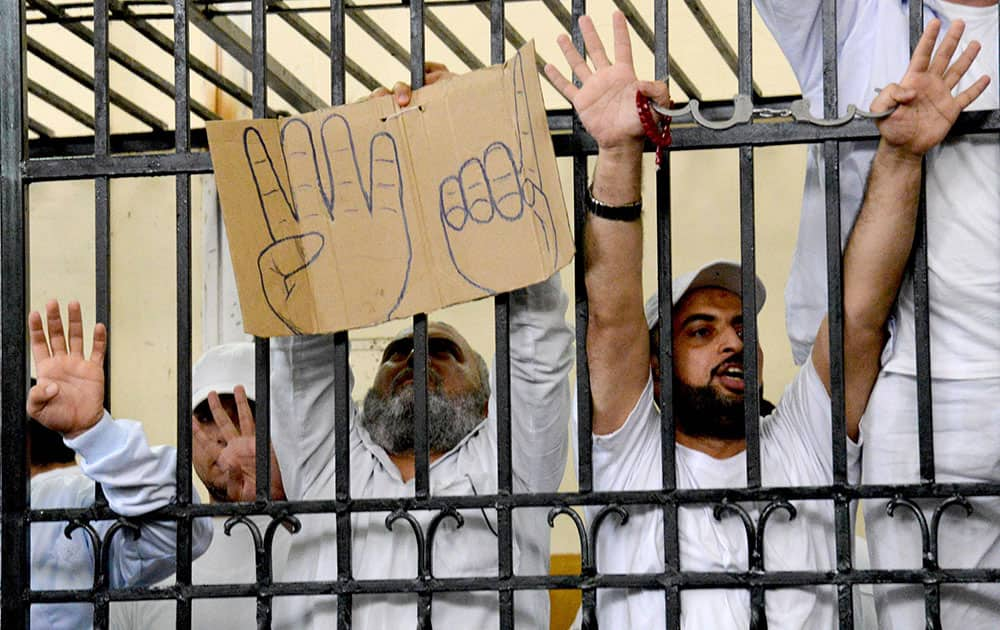 Supporters of the Muslim Brotherhood and other Islamists hold a cardboard sign with the `rabaa` symbol and from the defendants cage as they receive sentences ranging from death by hanging for one, life in prison for 13 and 8-15 years for the others after they were convicted of murder, rioting, and violence in a mass trial in Alexandria, Egypt.