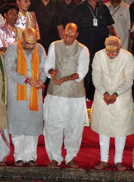 BJP leader and the next Prime Minister Narendra Modi with party President Rajnath Singh and party leader Amit Shah performing Ganga Aarti in Varanasi .