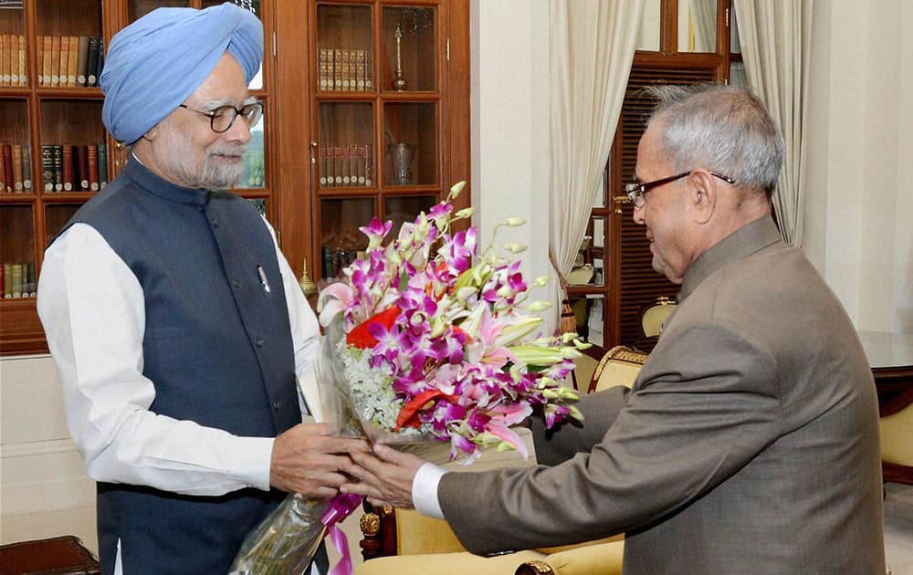 Prime Minister Manmohan Singh presents a bouquet to President Pranab Mukherjee during a meeting to submit his resignation at Rashtrapati Bhavan in New Delhi.