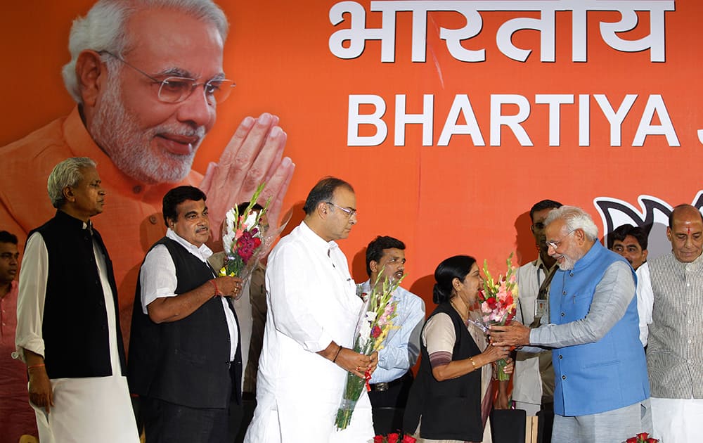 Narendra Modi, receives flowers from party leader Sushma Swaraj, as Arun Jaitley, center, and Nitin Gadkari, second left, wait their turn, at the party headquarters in New Delhi.