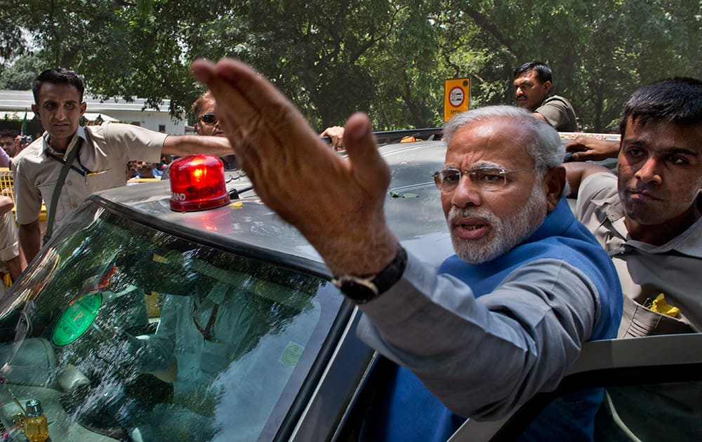 Narendra Modi greets the crowd standing on the footboard of his SUV outside the New Delhi airport.