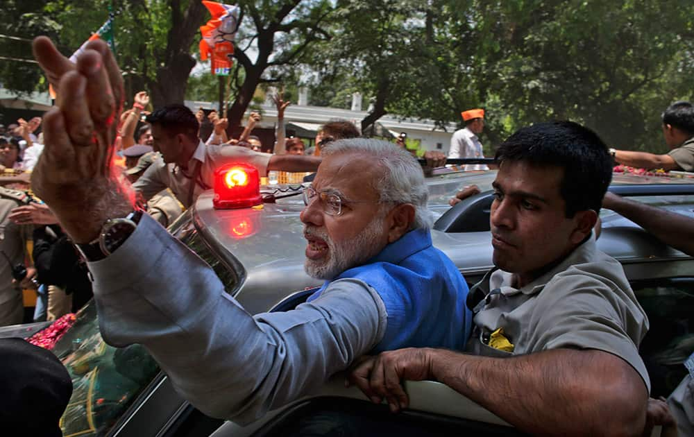 Narendra Modi greets the crowd standing on the footboard of his SUV outside the New Delhi airport.