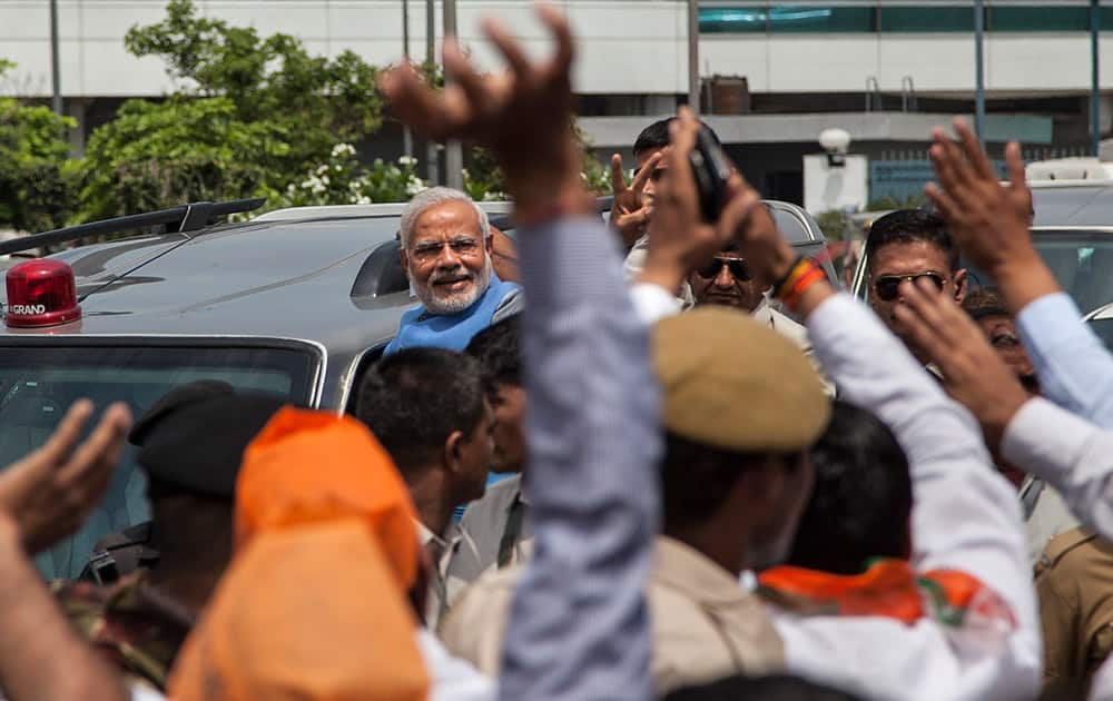 Narendra Modi greets the crowd standing on the footboard of his SUV outside the New Delhi airport.