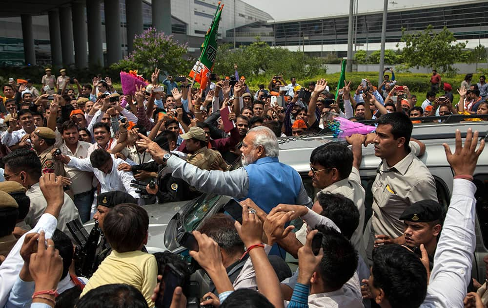 Bharatiya Janata Party (BJP) leader and India`s next prime minister Narendra Modi greets the crowd standing on the footboard of his SUV outside the New Delhi airport.