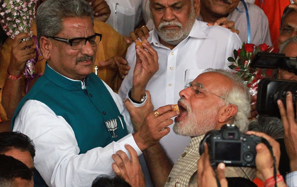 03:00 P.M.- Narendra Modi accepts sweets from a party leader at the party headquarters in Gandhinagar, Gujarat.