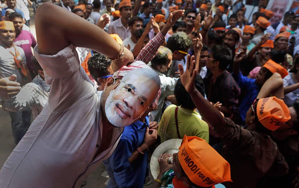 A Bharatiya Janata Party (BJP) supporter wears a mask of his leader Narendra Modi and celebrates preliminary results outside the party office in Guwahati.