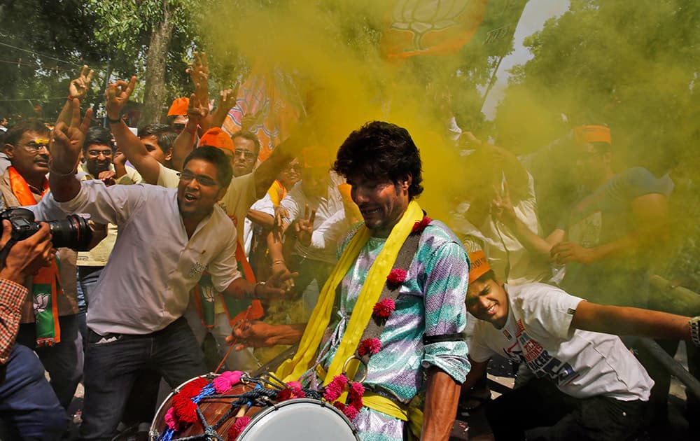 Bharatiya Janata Party (BJP) supporters throw colored powder and dance to celebrate preliminary results that showed the BJP winning by a landslide, outside the party headquarters in New Delhi.