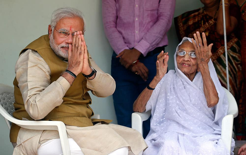 Narendra Modi greets the gathering as he sits with his 90-year-old mother Hiraben in Gandhinagar, Gujarat.