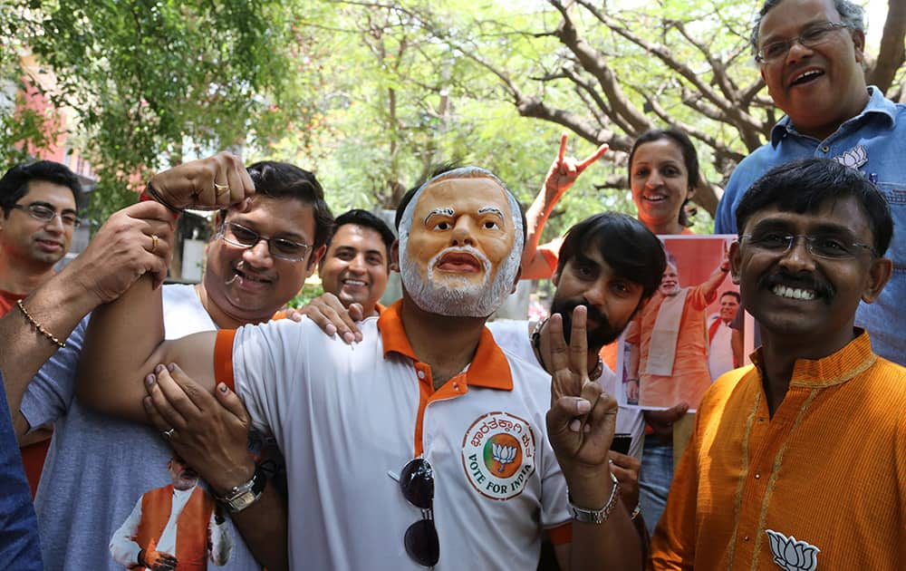 A supporter of India`s main opposition Bharatiya Janata Party (BJP) wears a mask of party leader and India`s next prime minister Narendra Modi as he celebrates with others preliminary results that show the BJP winning by a landslide, in Bangalore.