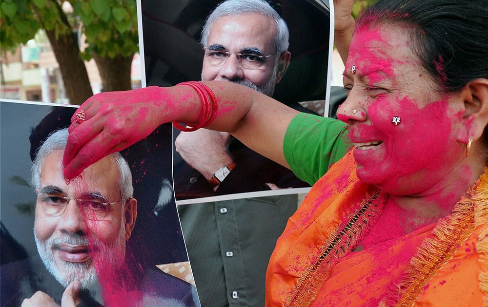 A BJP worker applying gulaal to Nerendra Modi`s picture celebrating the party`s victory in Lok Sabha polls, in Bikaner.