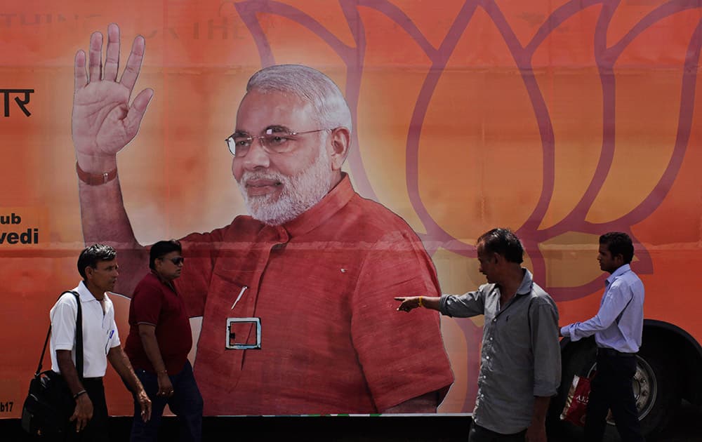 People walk past a bus with a photograph of Bharatiya Janata Party (BJP)`s prime ministerial candidate Narendra Modi as the same is prepared for celebrations anticipating his election victory in Ahmadabad.