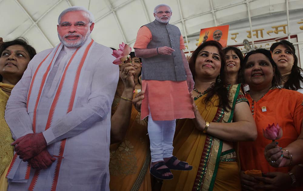 Supporters carry cut out photographs of Bharatiya Janata Party (BJP)`s prime ministerial candidate Narendra Modi as they gather at a Hindu temple to pray for his election victory in Ahmadabad.