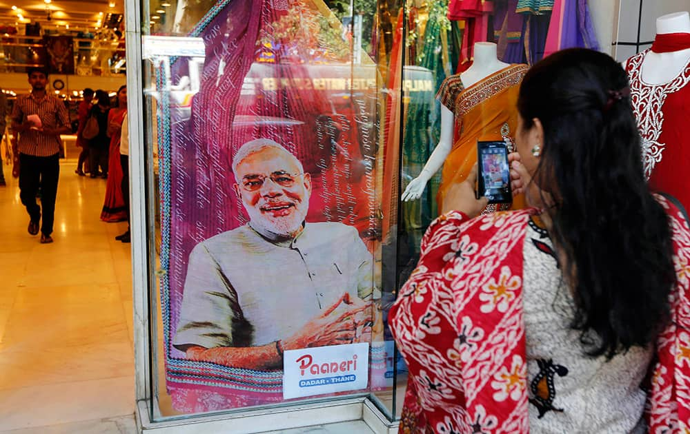 A woman takes a photograph of a sari printed with a portrait of Bharatiya Janata Party`s prime ministerial candidate Narendra Modi displayed at a garments shop in Mumbai.