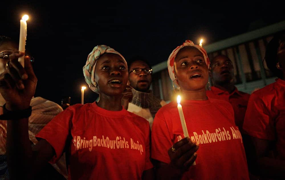 People hold candle light during a vigil to mark one month after the girls of government secondary school Chibok were kidnapped, in Abuja, Nigeria.