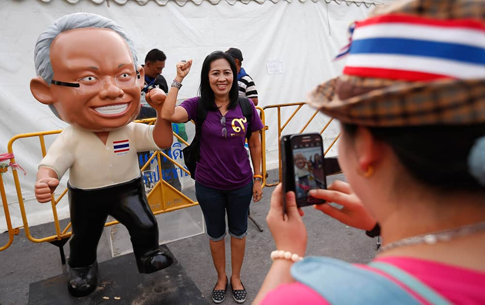 An anti-government protester poses for a picture with a life-size figure of protest leader Suthep Thaugsuban in Bangkok, Thailand.