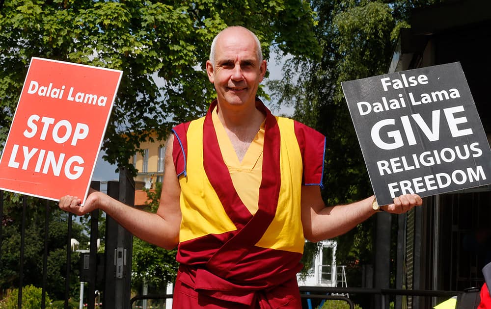 A man holds signs protesting against the Dalai Lama in Frankfurt, Germany. Around hundred western Buddhists and Tibetans called on the Dalai Lama to end discrimination and allow freedom of religion.