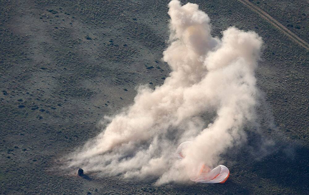 Dust rises as the Russian Soyuz TMA-11M space capsule, left, stands on the ground just after landing, some 150 kilometers (93 miles) southeast of town Dzhezkazgan, Kazakhstan.