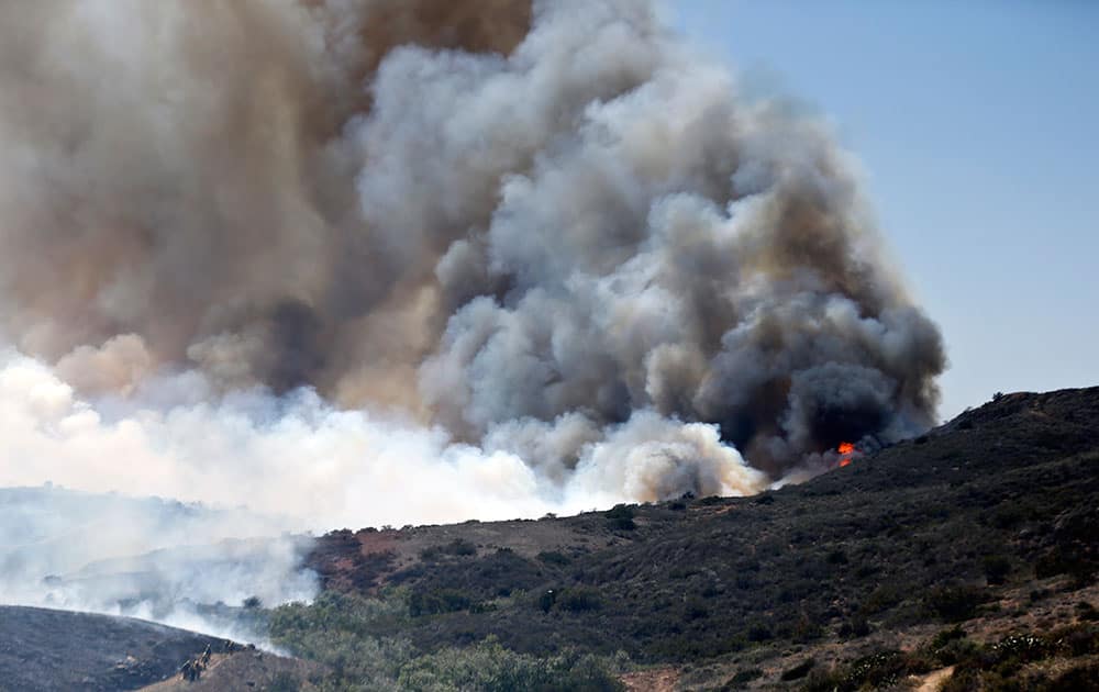 Billowing smoke rises from flames as firefighters begin the trek up the hills to battle a wild fire, in San Diego. 