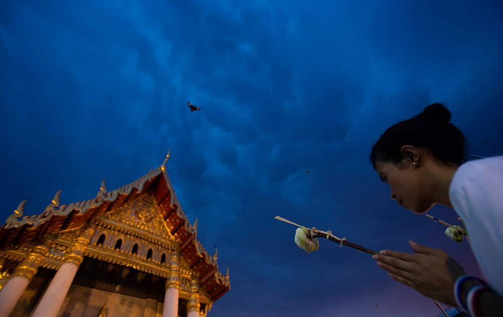 A Thai Buddhist carrying a lotus bud prays in front of Marble Temple in Bangkok as part of Wesaka Bucha activities. Wesaka Bucha, the most important Buddhist holy day of the year, marks the birth, enlightenment and death of Lord Buddha.