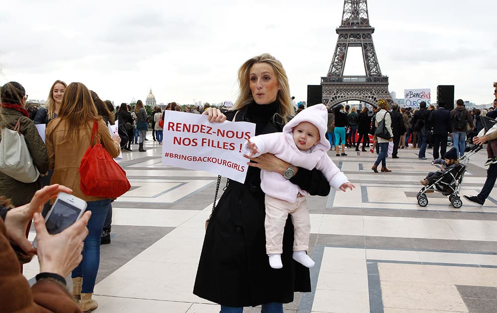 A woman holds her baby and a poster reading `Bring Back our Girls` during a rally at the Trocadero, in front of the Eiffel Tower, to support the release of the kidnapped girls in Nigeria, in Paris.