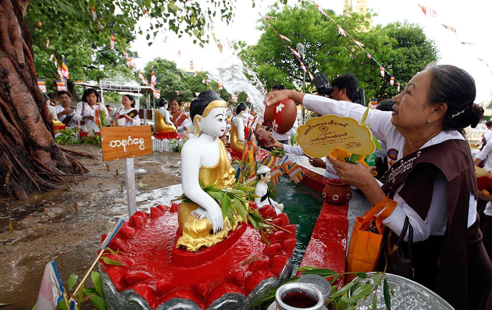 A Buddhist devotee pours water to a Bayan tree over a Buddha statue at Shwedagon Pagoda during the Full Moon Day of Kasone, known as Buddha`s Birthday, in Yangon.