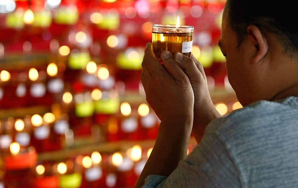 A Buddhist devotee holds an oil lamp as he offers prayers on Wesak Day at the Thai Buddhist Chetawan Temple in Petaling Jaya, near Kuala Lumpur.