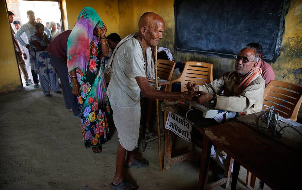 A polling official marks the finger of an elderly man with indelible ink before he casts his vote at a polling station in Kunwarpur village, about 40 kilometers (25 miles) northwest of Jaunpur district, in the northern Indian state of Uttar Pradesh.