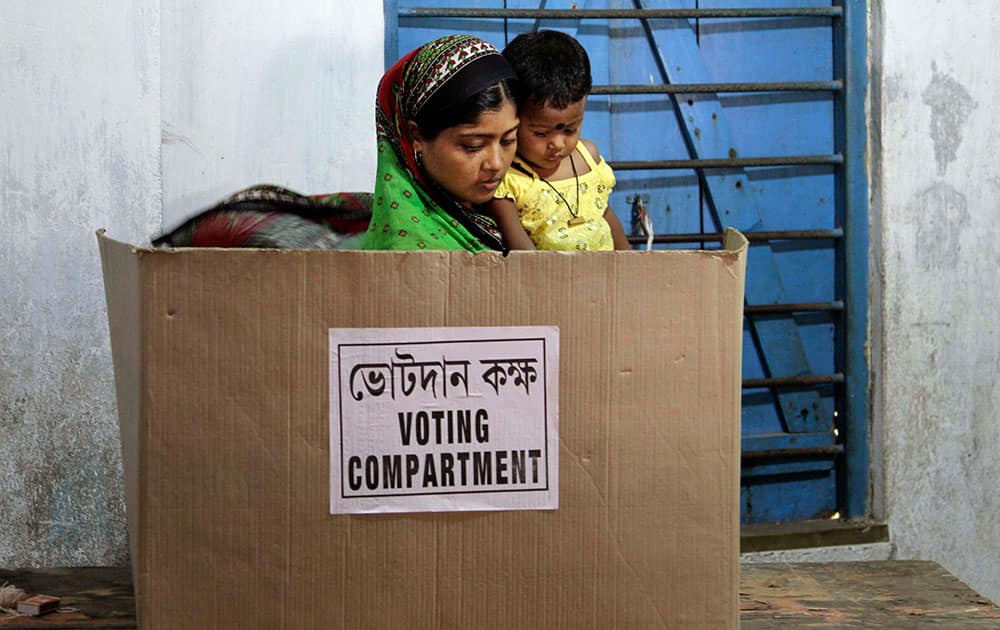 A woman carries her child while casting her vote on the final day of polling in Kamalgaji, on the outskirts of Kolkata.