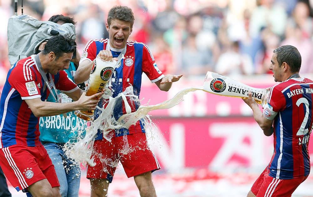 Bayern`s Philipp Lahm, from right, Thomas Mueller and Claudio Pizarro of Peru celebrate with beer after winning the German Soccer Championship after the season`s last match between FC Bayern Munich and VfB Stuttgart, in Munich.