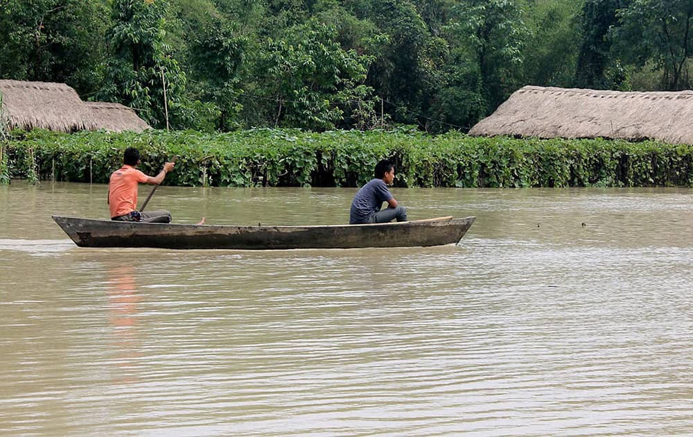 People move with the help of a boat in the flood waters of Dibrusaikhowa River at Guijan area of Assam.