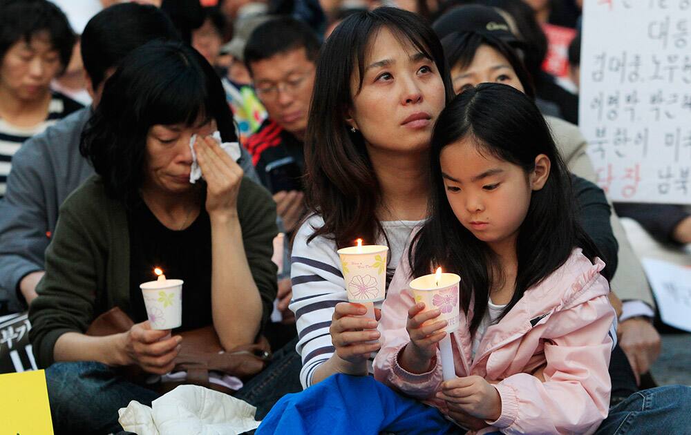 A mother and her daughter hold candles during a rally to pay tribute to the victims and missing passengers of the sunken ferry Sewol in Seoul, South Korea.