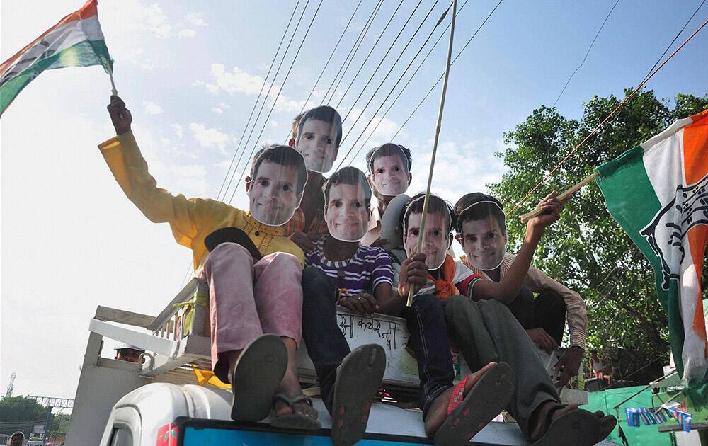 Children, wearing mask of Congress Vice President Rahul Gandhi, wave Congress party flags during an election road show in Varanasi.