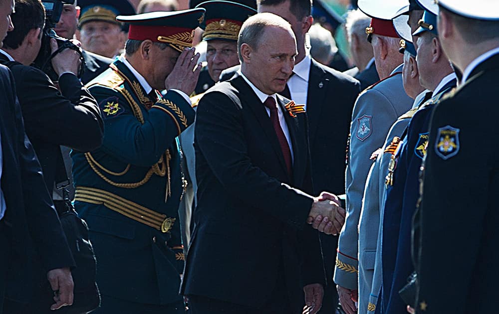 Russian President Vladimir Putin shakes hands with WWII veterans as Defense Minister Sergei Shoigu salutes after the Victory Day Parade in Red Square in Moscow, Russia.