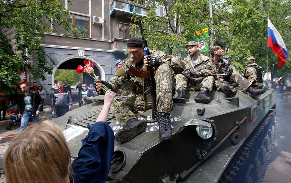 A woman welcomes a pro-Russian gunman atop an armored personal carrier during a Victory Day celebration, which commemorates the 1945 defeat of Nazi Germany, in the center of Slovyansk, eastern Ukraine.