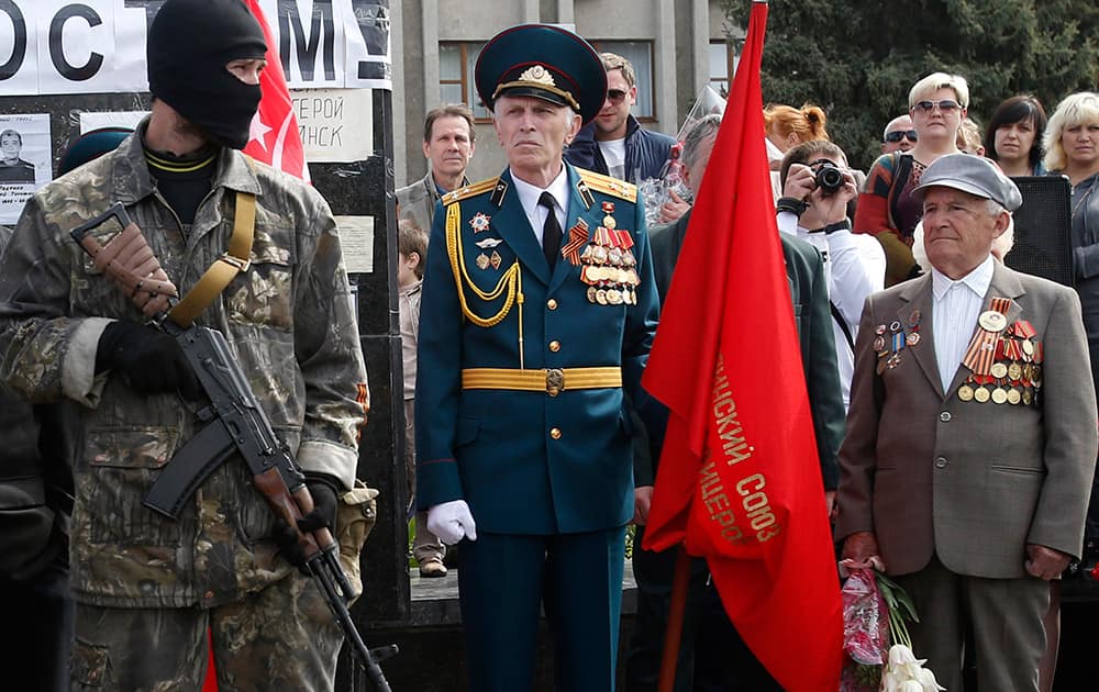 A pro-Russian gunman stands guard in front of World War II veterans, during a Victory Day celebration, which commemorates the 1945 defeat of Nazi Germany, in the center of Slovyansk, eastern Ukraine.