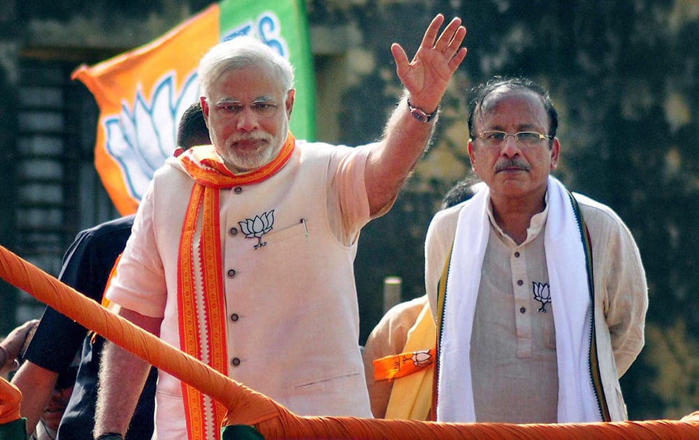 BJP PM candidate Narendra Modi waves during an election road show in Varanasi.