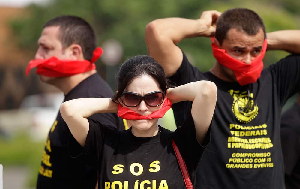 Federal police wearing T-shirts that read in Portuguese `SOS Federal Police` cover their mouths with bandanas as a way to protest their leaders` recommendation to not protest, as they demand better labor conditions outside the venue where Brazil`s coach is announcing his squad for the upcoming World Cup in Rio de Janeiro, Brazil.