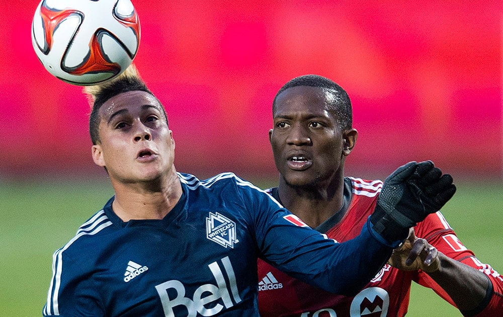 Toronto FC defender Doneil Henry, right, battles for the ball against Vancouver Whitecaps forward Erik Hurtado, left, during first half semi-final Amway Canadian Championship soccer action in Toronto.