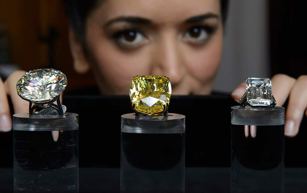 A Sotheby`s employee shows three exceptional diamonds during a preview at the Sotheby`s, in Geneva, Switzerland.